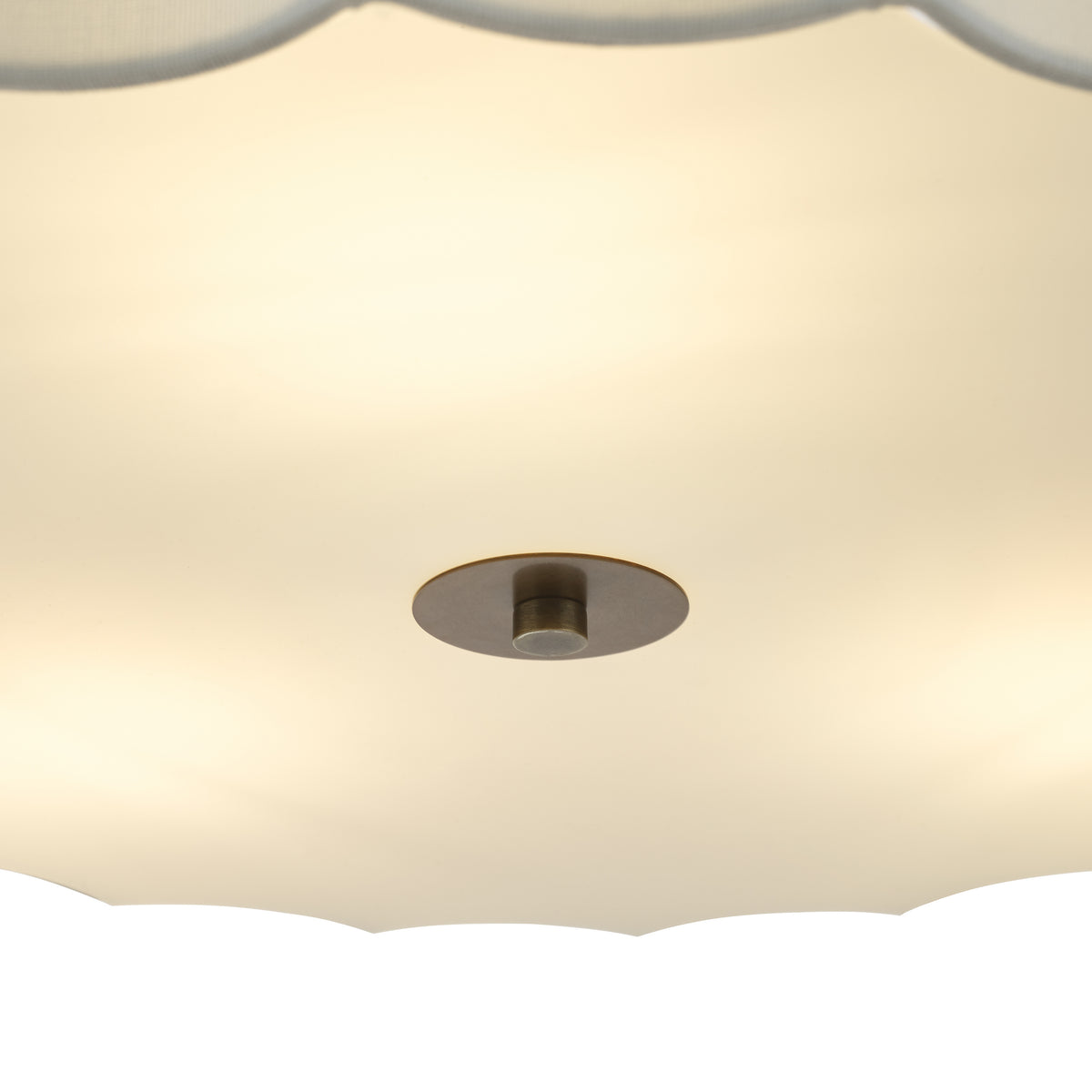 Close-up of a ceiling light fixture with a scalloped edge and a bronze-colored central mount