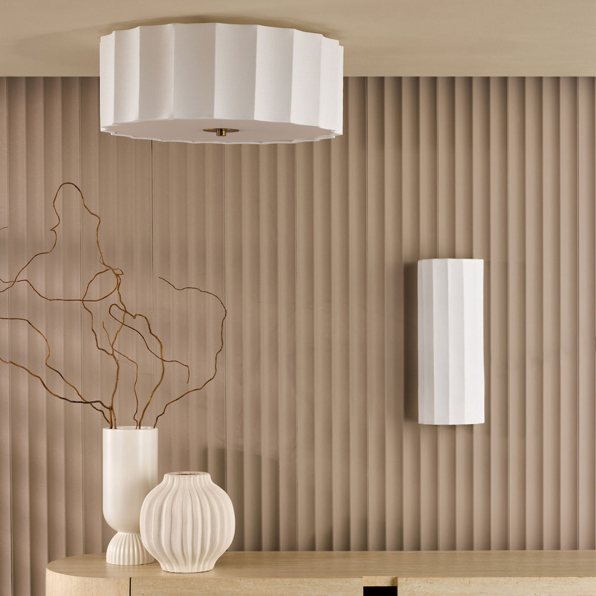 White fluted ceiling light and wall sconce above a console table with two white vases and branches