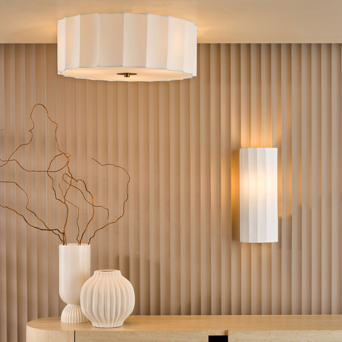 Two white pleated fabric light fixtures illuminate a textured beige wall above a wooden console table