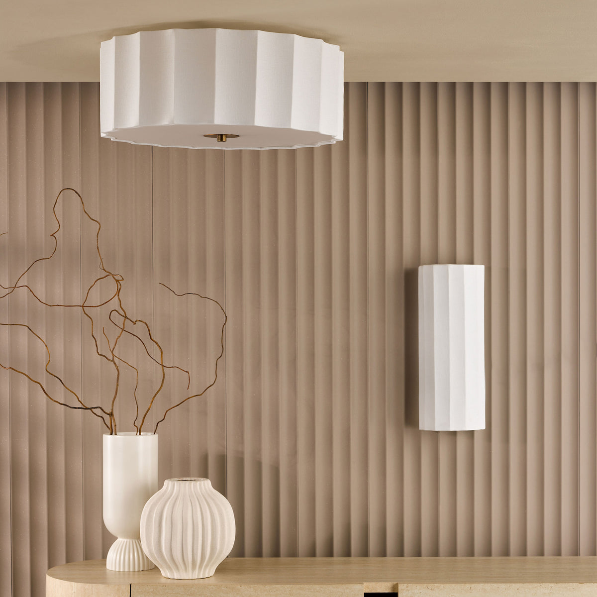 White fluted ceiling light and wall sconce above a console table with vases and branches