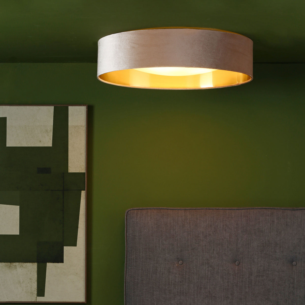 A ceiling light with a gold interior and a grey fabric exterior, mounted on a dark green ceiling