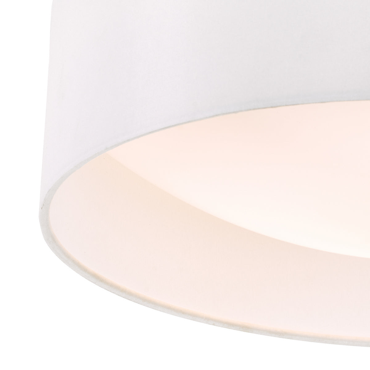 Close up of a white fabric lampshade with a warm glow from inside