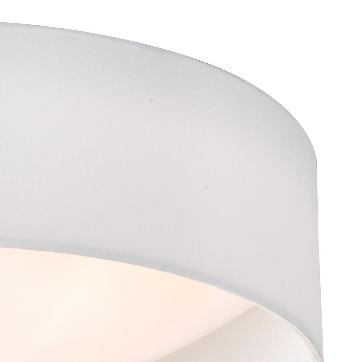 Close up of a white fabric lampshade with a soft glow from inside