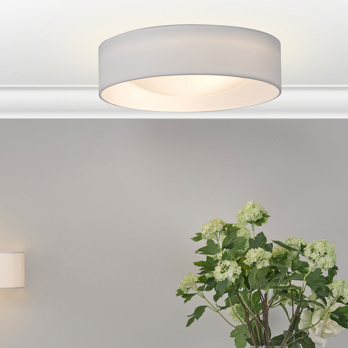 White ceiling light with a drum shade and a bouquet of green and white flowers