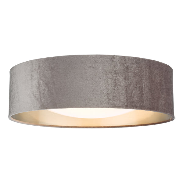 Grey velvet drum lampshade with a light-colored interior, illuminated from within