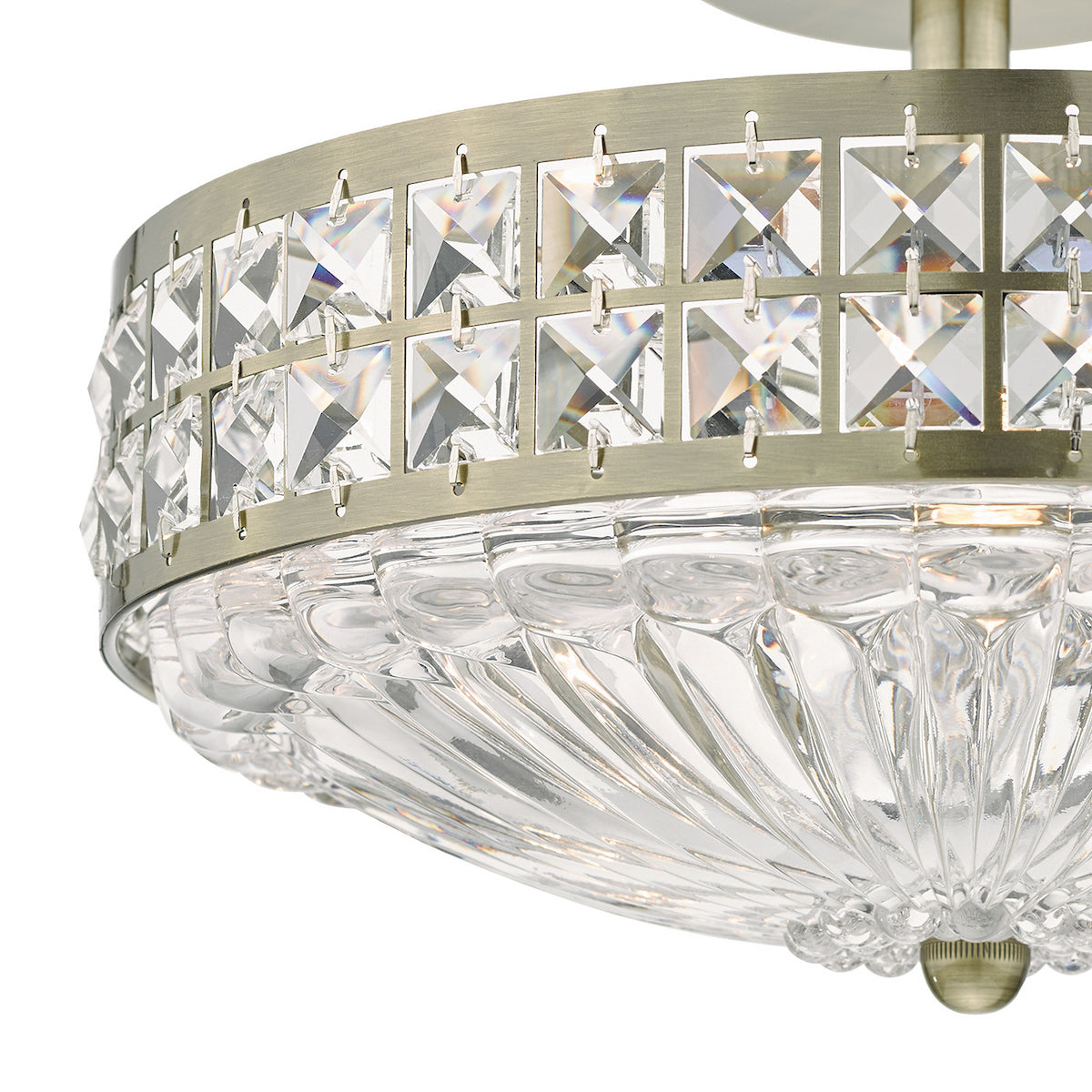 Close-up of a flush mount light fixture with a clear, fluted glass shade and a band of square crystals.