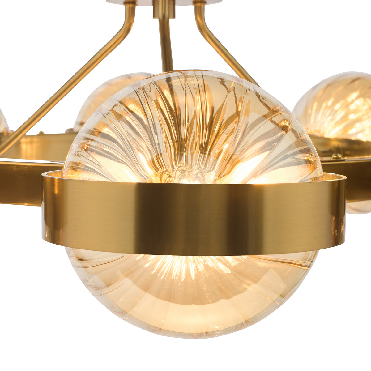 Close-up of a modern brass chandelier with amber ribbed glass globes, emitting a warm glow.