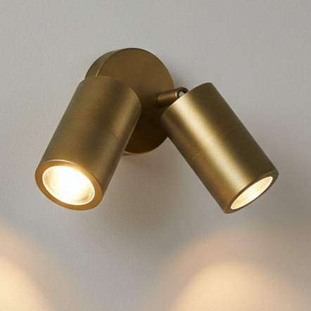 Two brass spotlights on a white wall