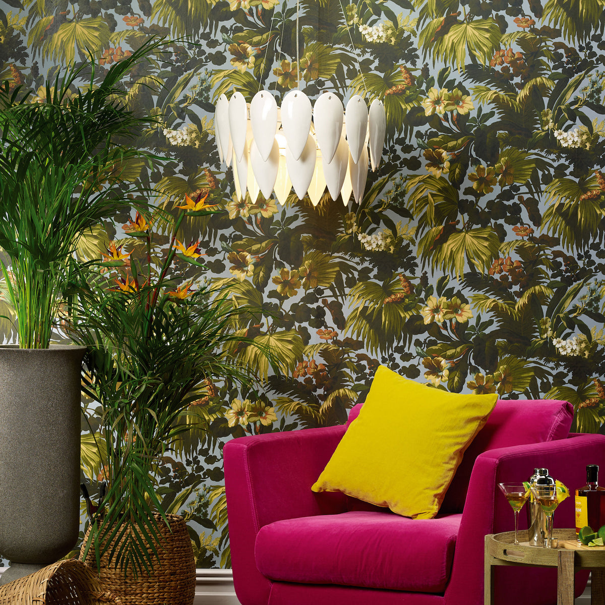 A vibrant room with tropical wallpaper, a fuchsia armchair, and a white petal-shaped chandelier.