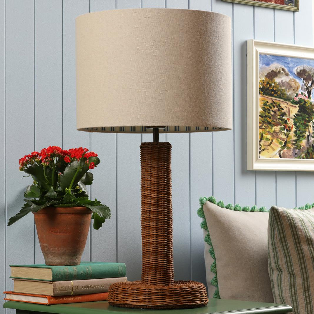 Table lamp with a cylindrical woven rattan base and a beige drum shade