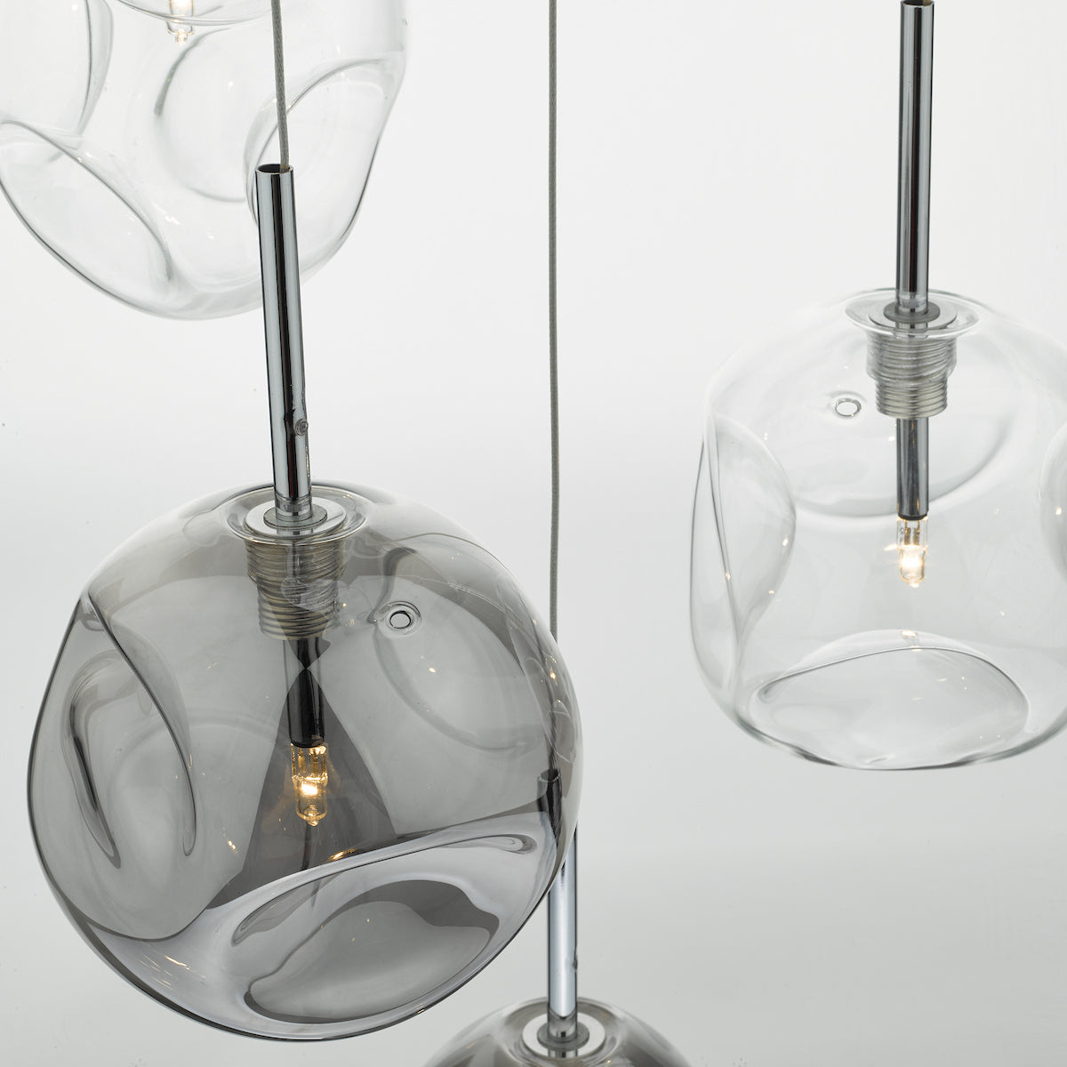 Close-up of three pendant lights with clear and smoked glass shades, hanging from thin wires.