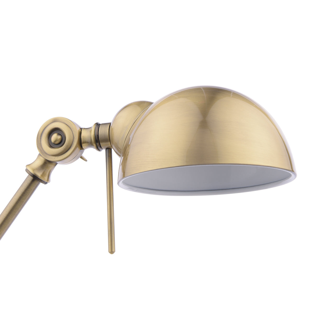Close-up of a brass desk lamp with an adjustable arm and a dome-shaped shade.