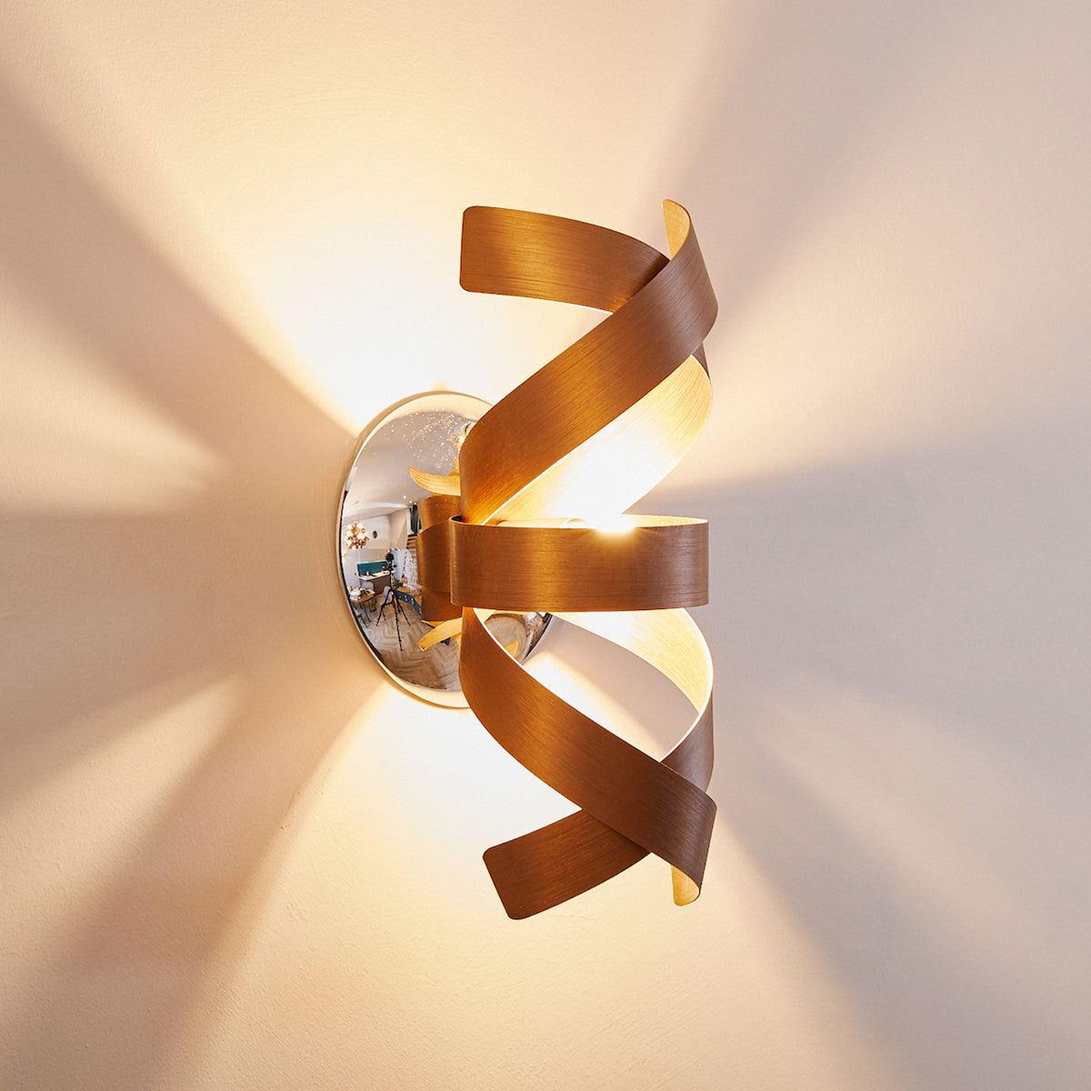Modern wall sconce with a spiral wooden shade, casting warm light upwards and downwards.