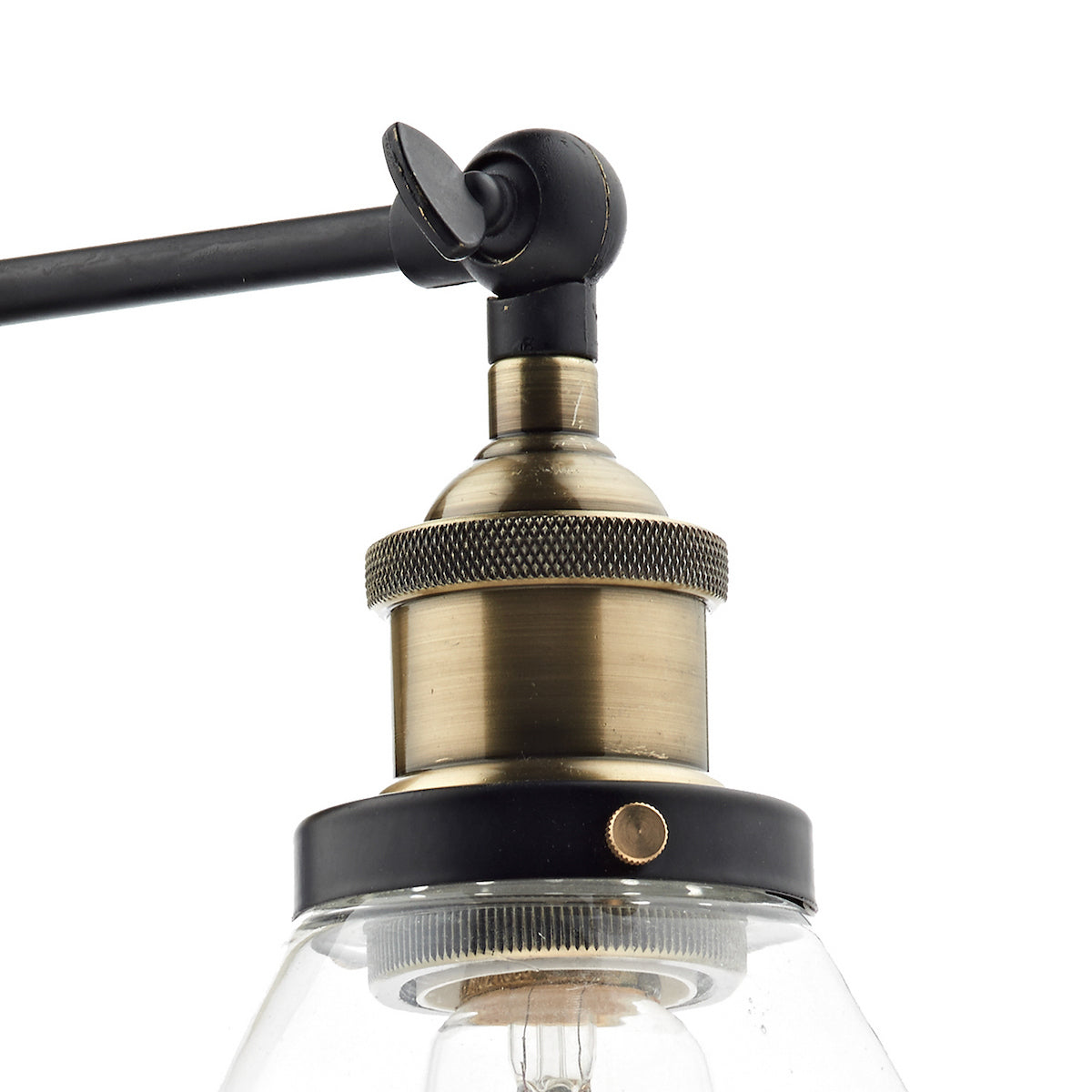 Close-up of a brass light fixture with a clear glass shade and black accents.
