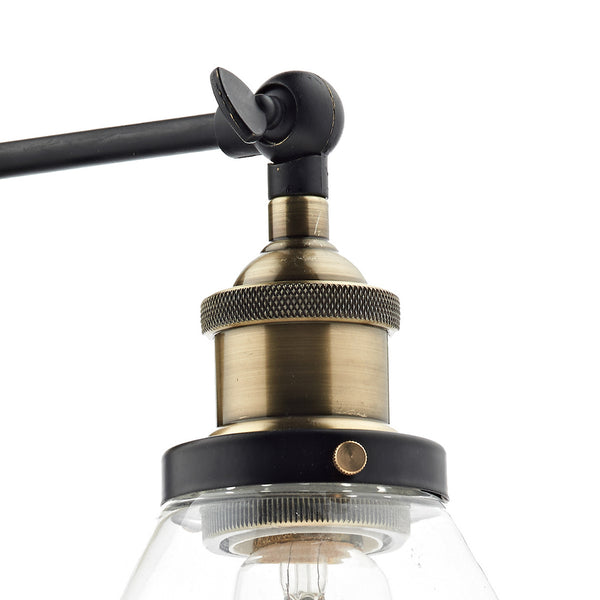 Close-up of a brass light fixture with a clear glass shade and black accents.