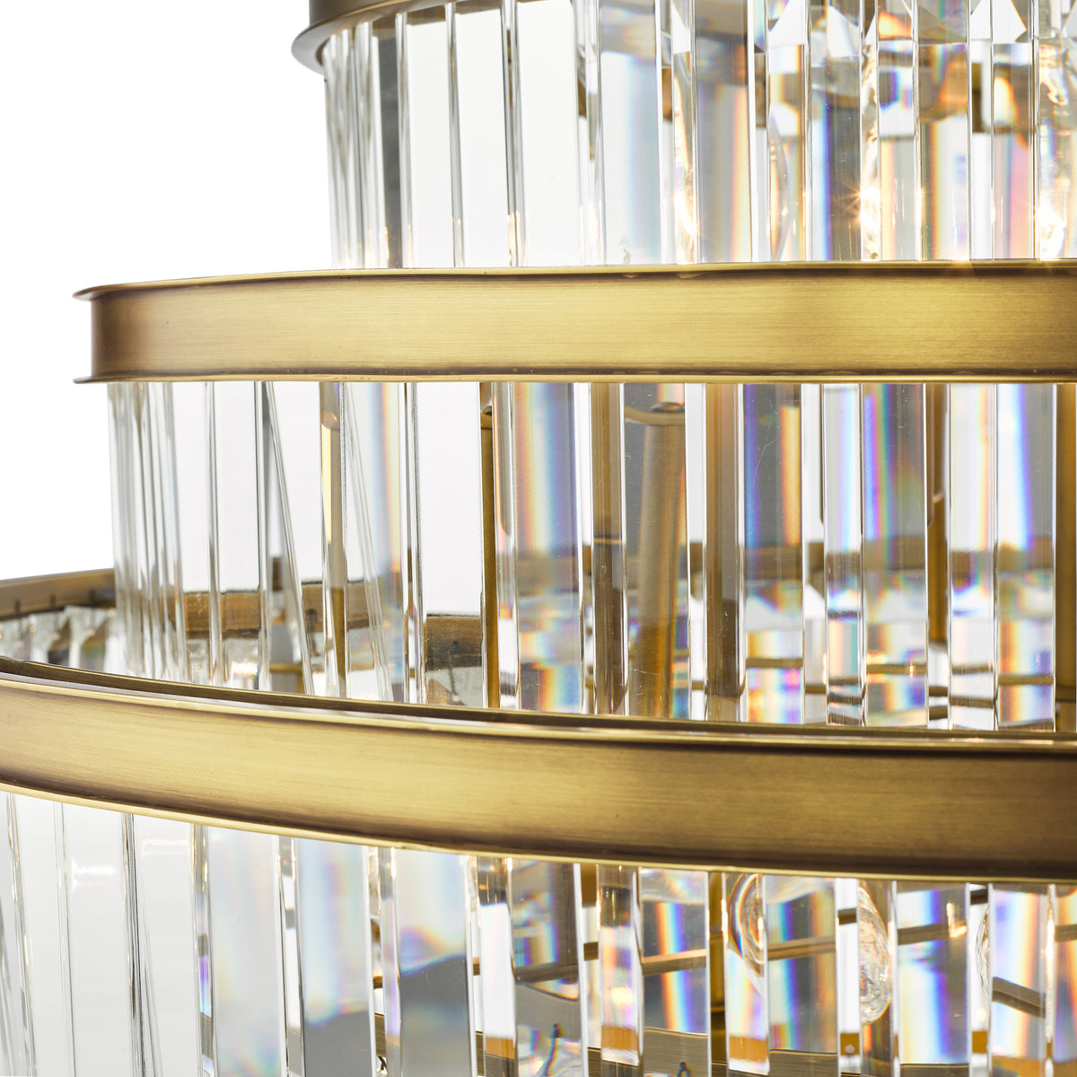 Close up of a tiered chandelier with clear rectangular crystals and brass bands