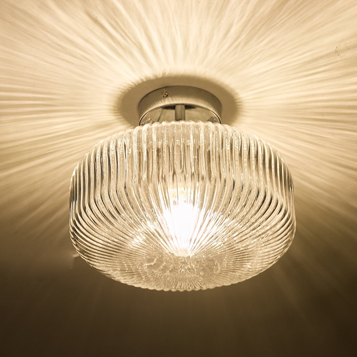 A ribbed glass ceiling light casts a warm, starburst pattern on the white ceiling.