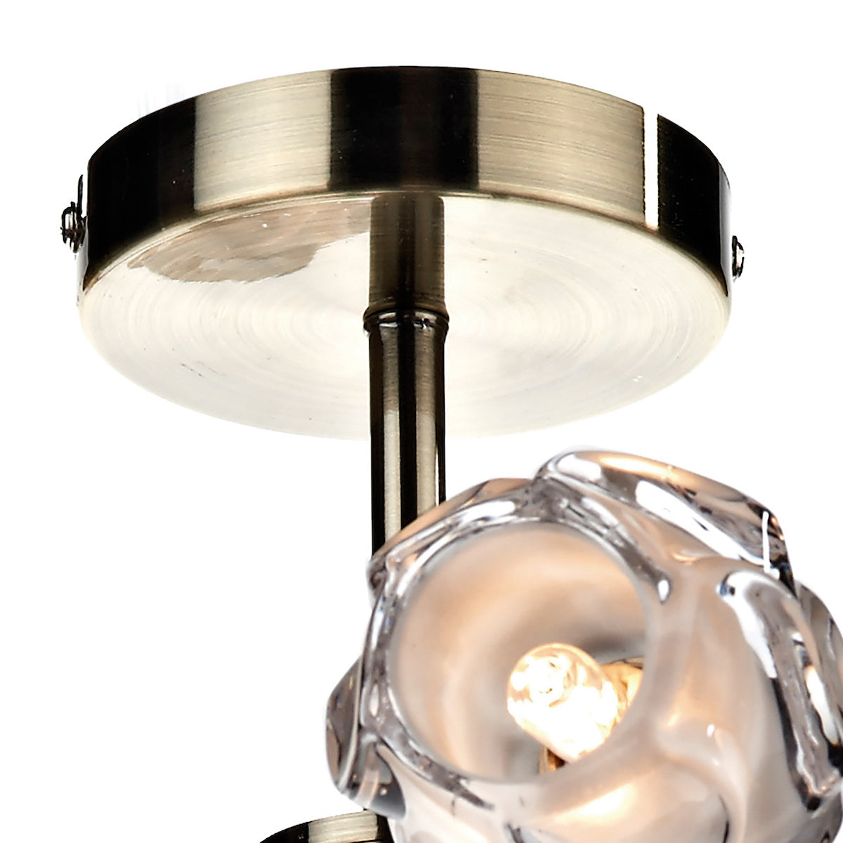 Close-up of a ceiling light fixture with a brushed brass base and a clear, textured glass shade.