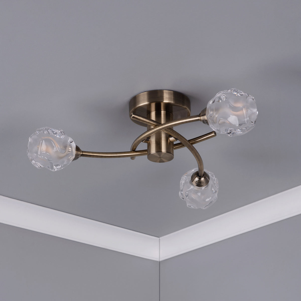 Bronze ceiling light with three frosted glass shades, mounted on a gray ceiling with white crown molding.