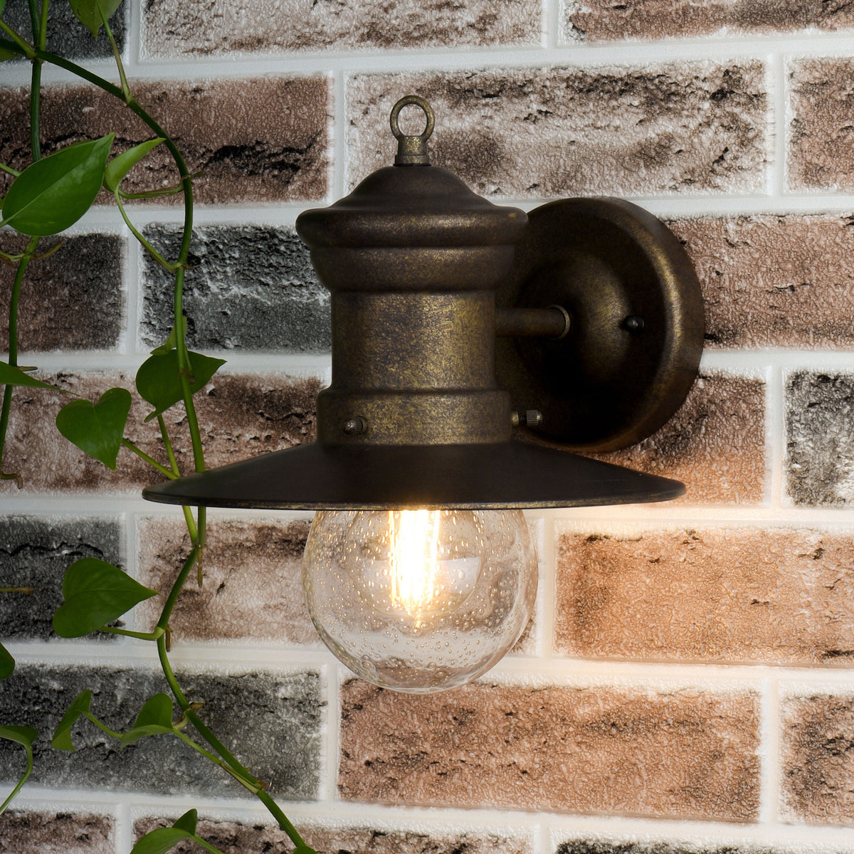 A bronze outdoor wall light with a seeded glass globe and an Edison bulb, mounted on a brick wall.