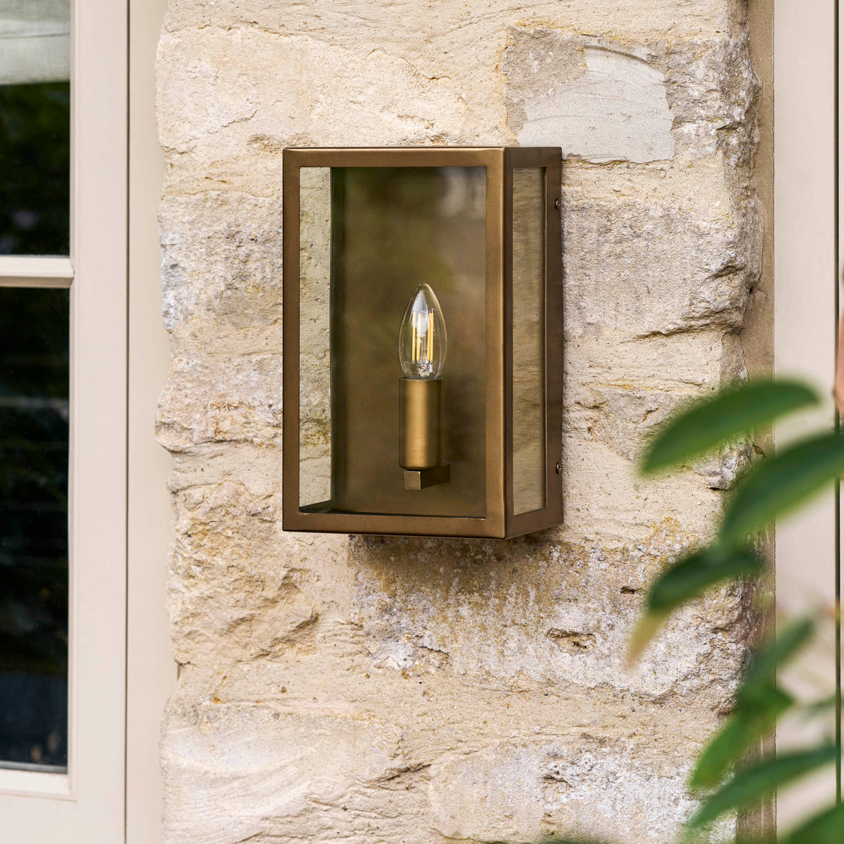 Sandford Outdoor Single Box Lantern in antique brass mounted on a light stone wall