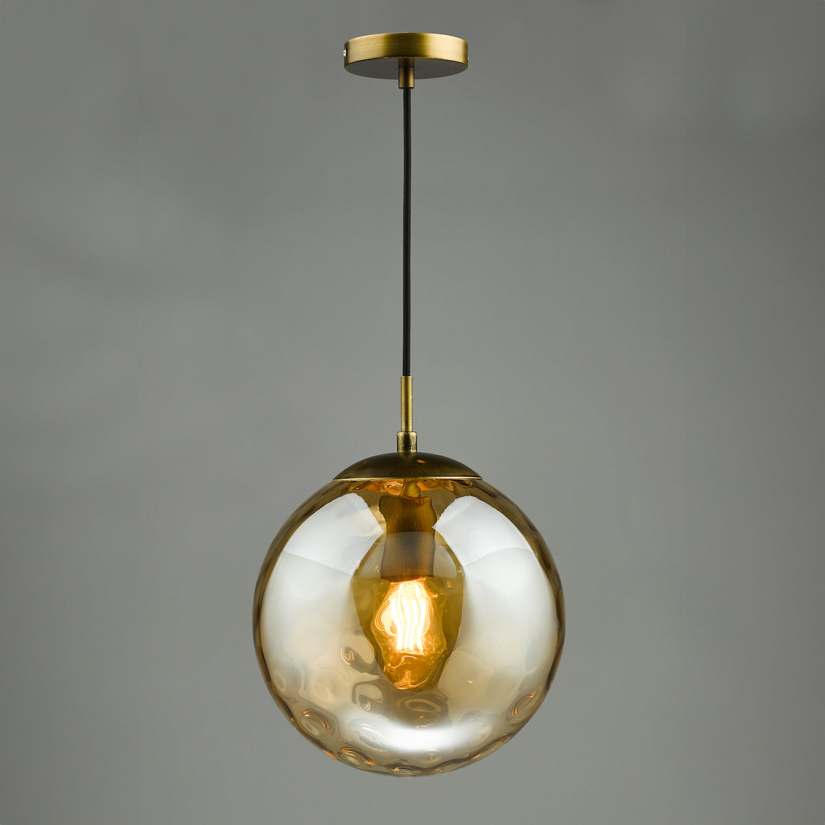 Textured amber glass globe pendant light with a brass fixture and exposed filament bulb.