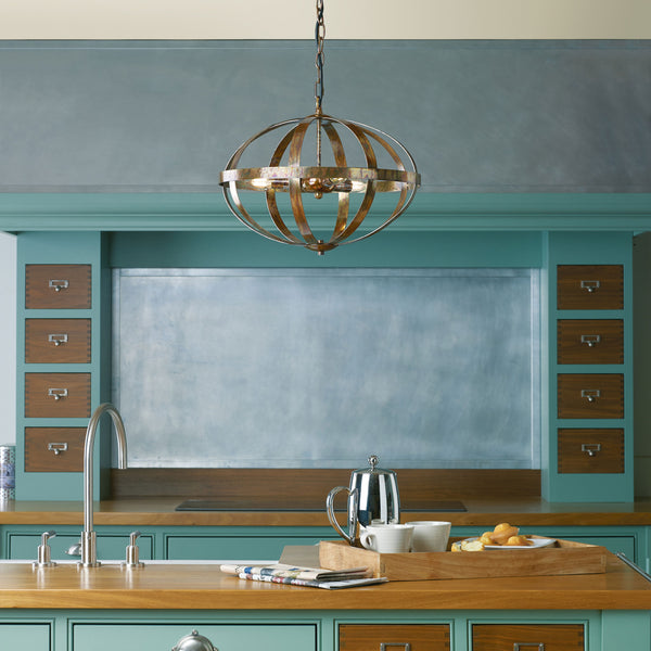A kitchen with teal cabinets, wooden countertops, and a large, ornate metal chandelier hanging above.