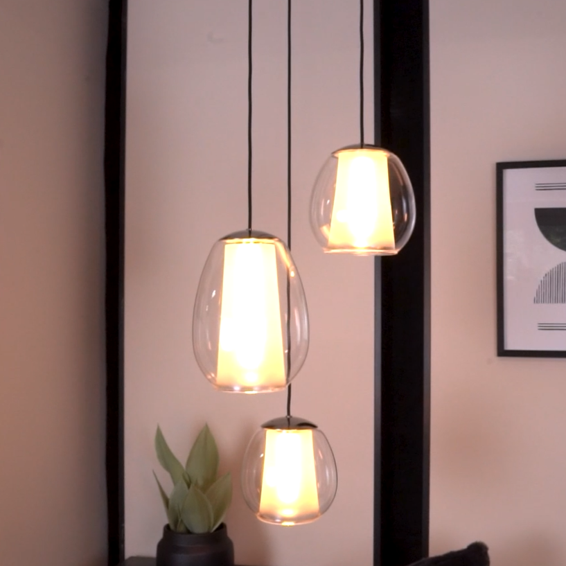 Three pendant lights with clear glass shades and glowing white interiors hang from the ceiling