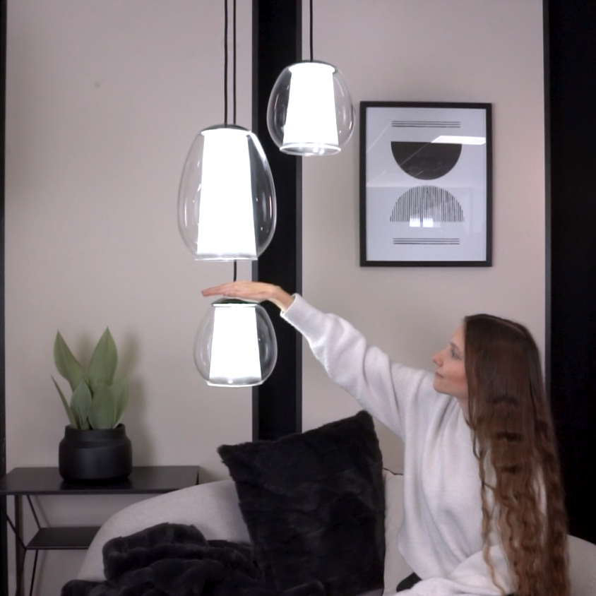 Woman touching a pendant light in a modern living room with two other pendant lights