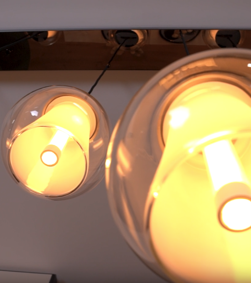 Two clear glass pendant lights with glowing yellow bulbs hanging from a ceiling fixture