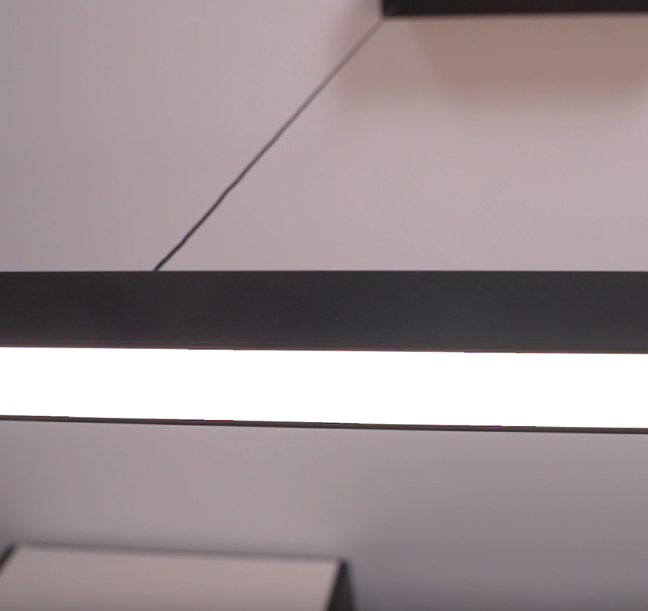Close up of a black linear pendant light with a bright white LED strip