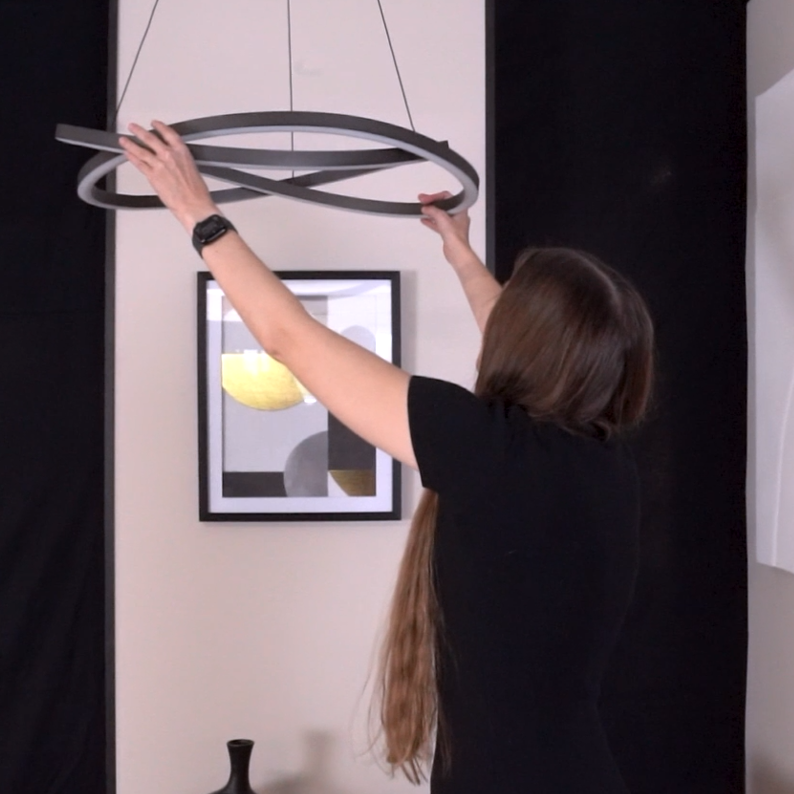 Woman adjusting a modern circular LED chandelier