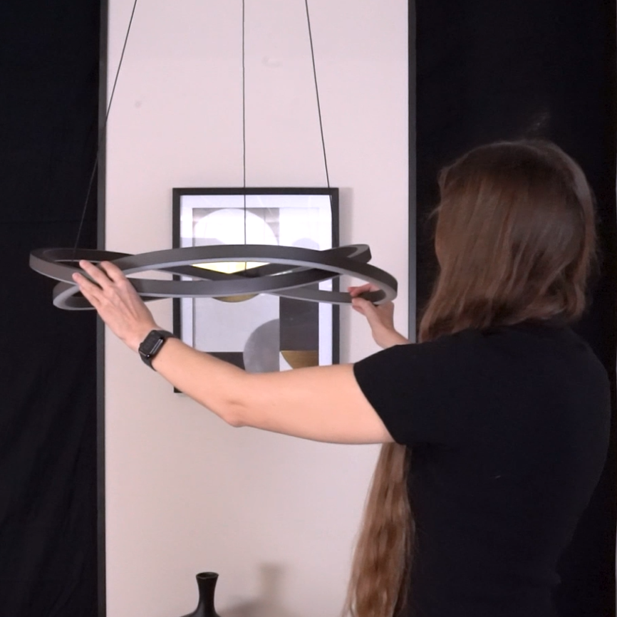 Woman adjusting a modern, dark grey, intertwined ring chandelier