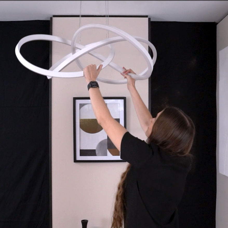 Woman installing a modern white circular chandelier