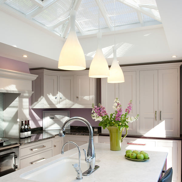 Bright kitchen with skylight, pendant lights, white cabinets, and a vase of flowers on the island.