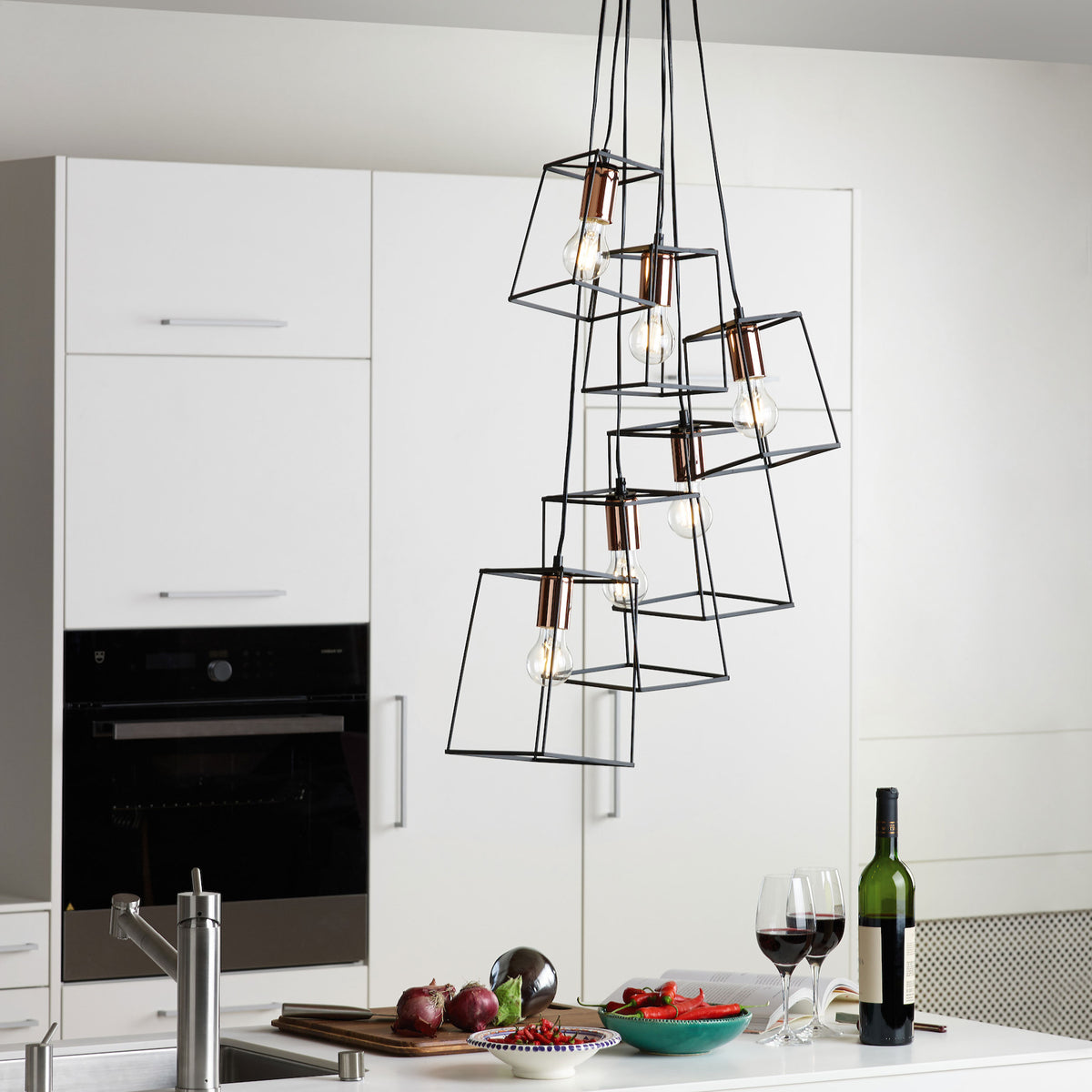 Modern kitchen with white cabinets, a black oven, and a unique hanging light fixture.