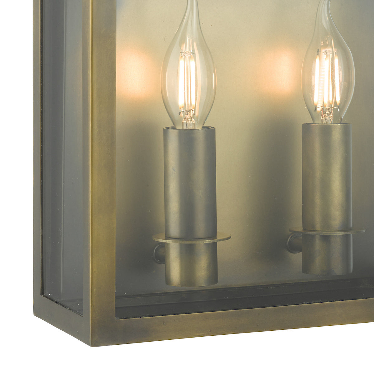 Close-up of a bronze outdoor wall light with two lit candle-style bulbs.