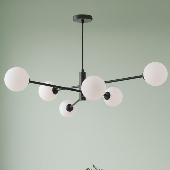 Modern black chandelier with six white spherical glass shades extending from a central rod.
