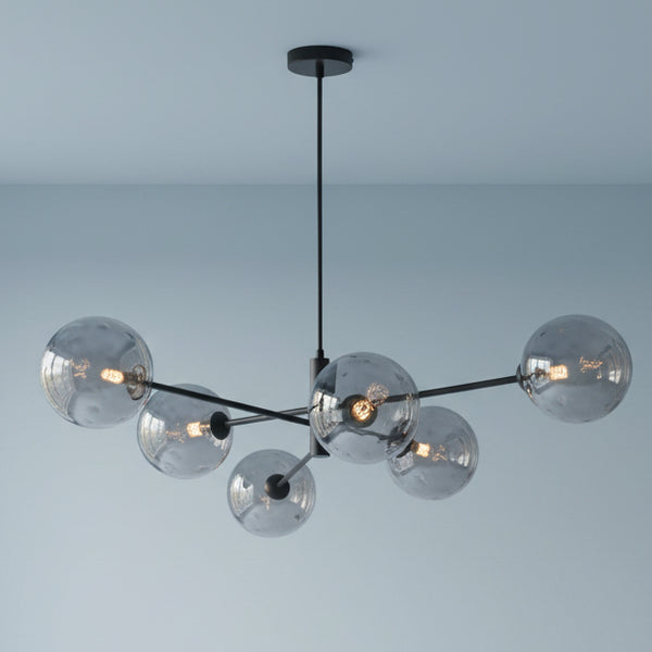 Modern black chandelier with six smoky grey glass globes, each containing an illuminated bulb.