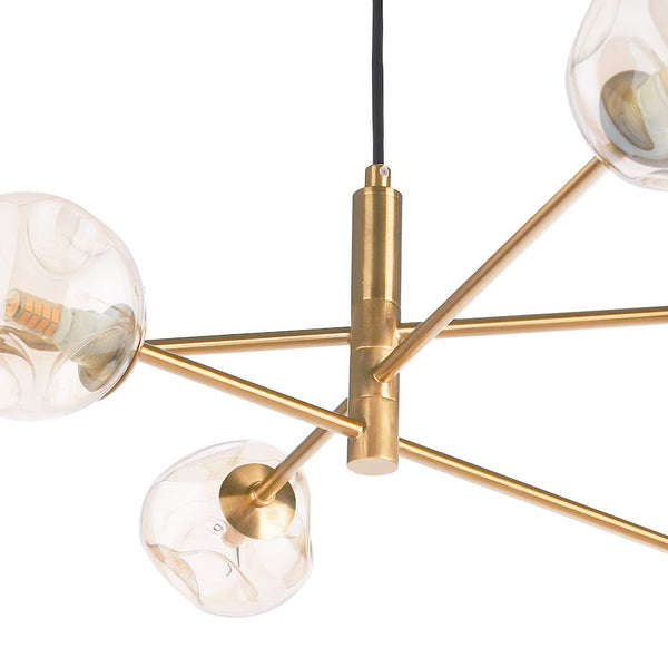 Modern brass chandelier with six clear, textured glass globes, each containing a small bulb, on a white background.
