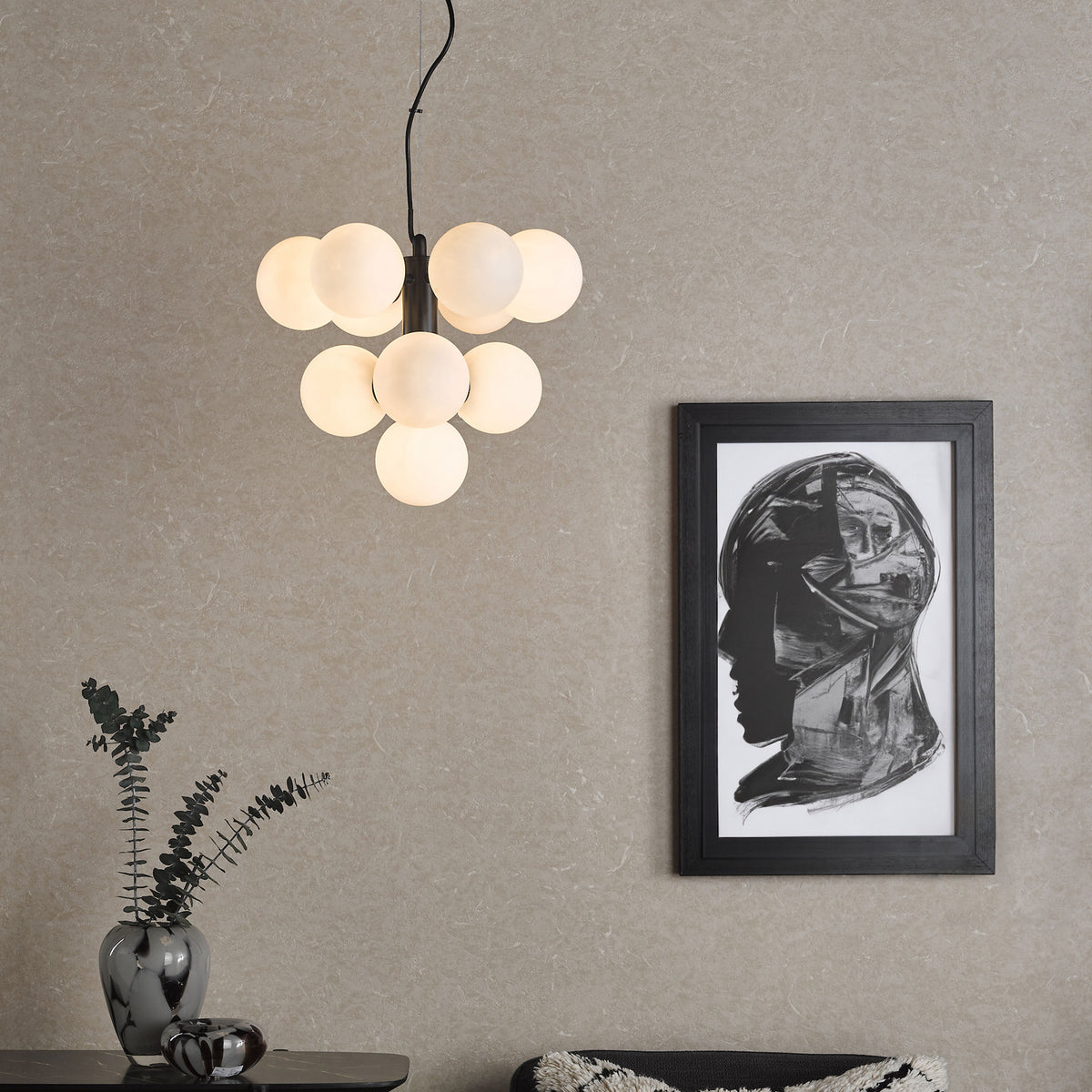 Modern living room with a cluster pendant light, framed abstract art, and decorative vase with eucalyptus.