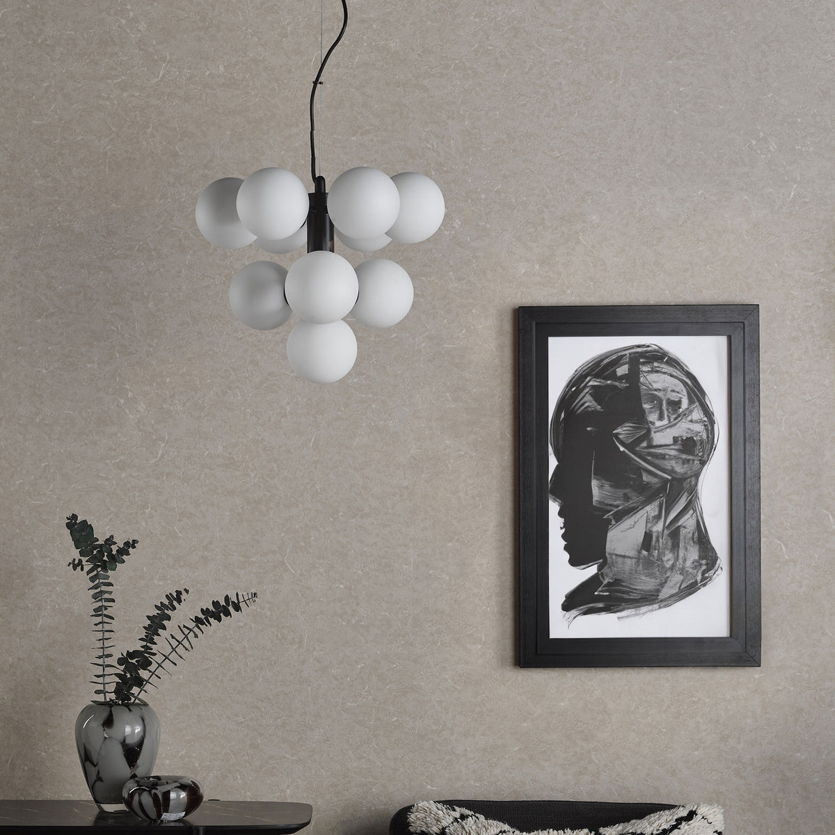 Modern living room with a unique white spherical chandelier, abstract framed art, and decorative vases.