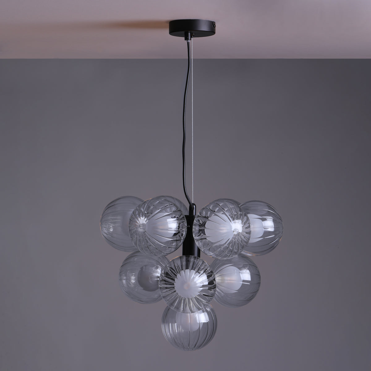 Modern chandelier with multiple clear, ribbed glass globes hanging from a black fixture.