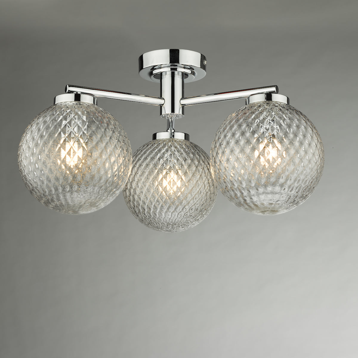 Chrome ceiling light with three textured glass globe shades.