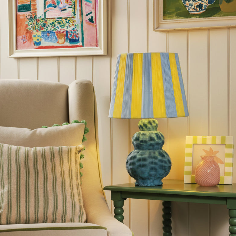 Joules Whitby table lamp with matt blue base and blue and yellow striped fabric shade on a green side table