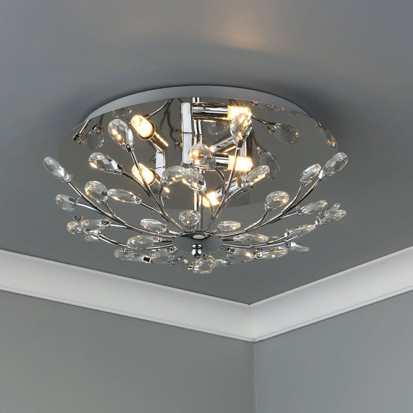 A modern, chrome ceiling light with numerous clear crystal accents, illuminating a gray room.