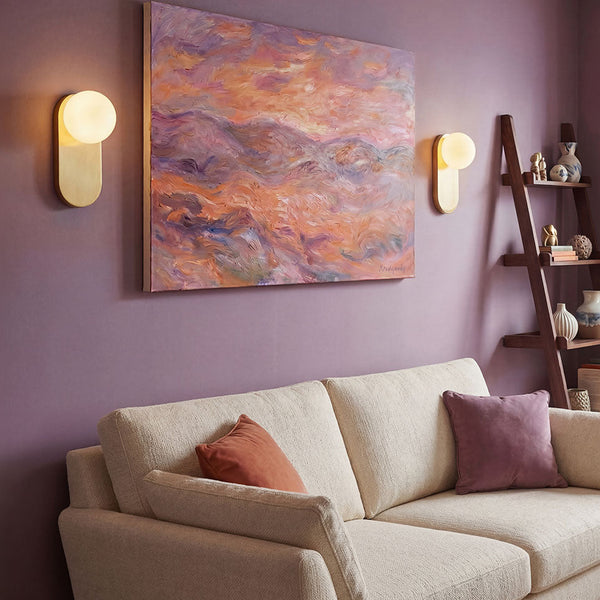 Alora Mood Ariel wall light in brushed gold with opal glass diffuser mounted on a purple wall