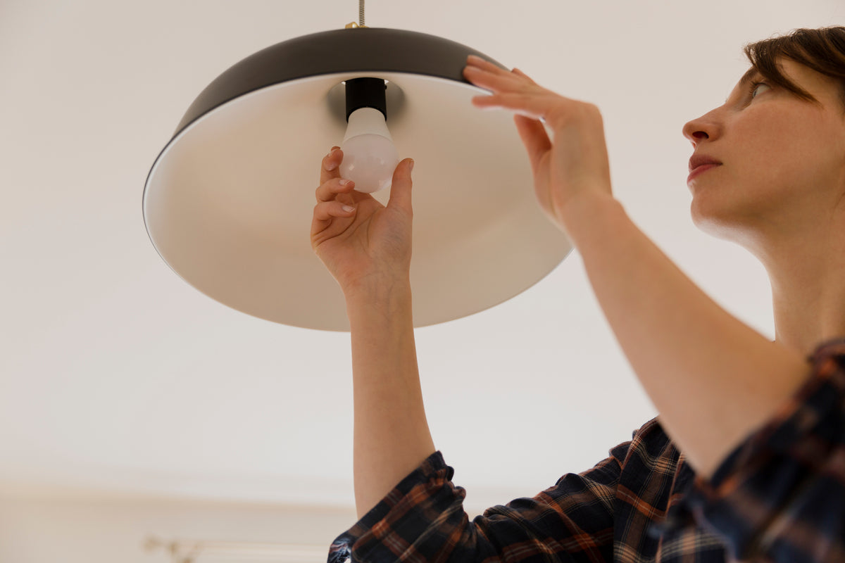 Woman changing a lightbulb in a ceiling fixture