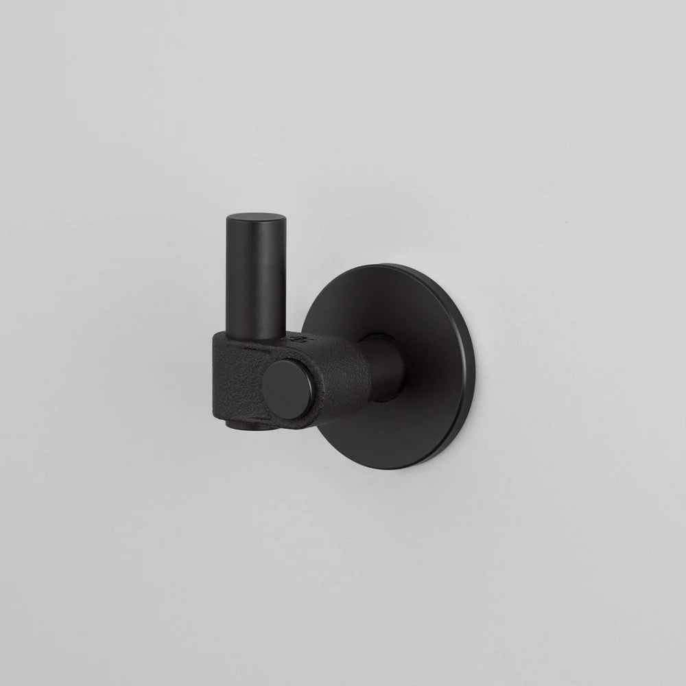Black metal wall hook with a cylindrical top and a textured base
