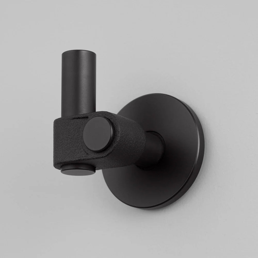 Black wall-mounted light fixture with a cylindrical arm and a round base